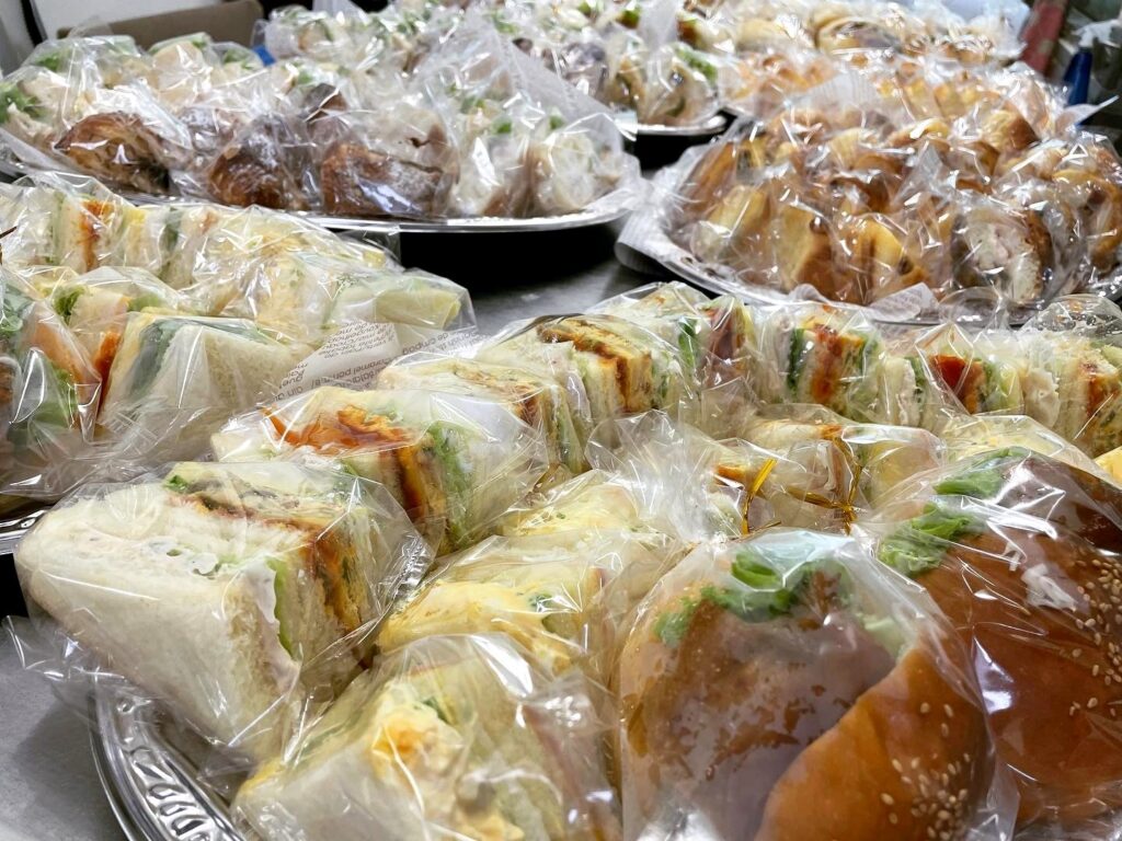 Individually wrapped sandwiches and bread on a platter
