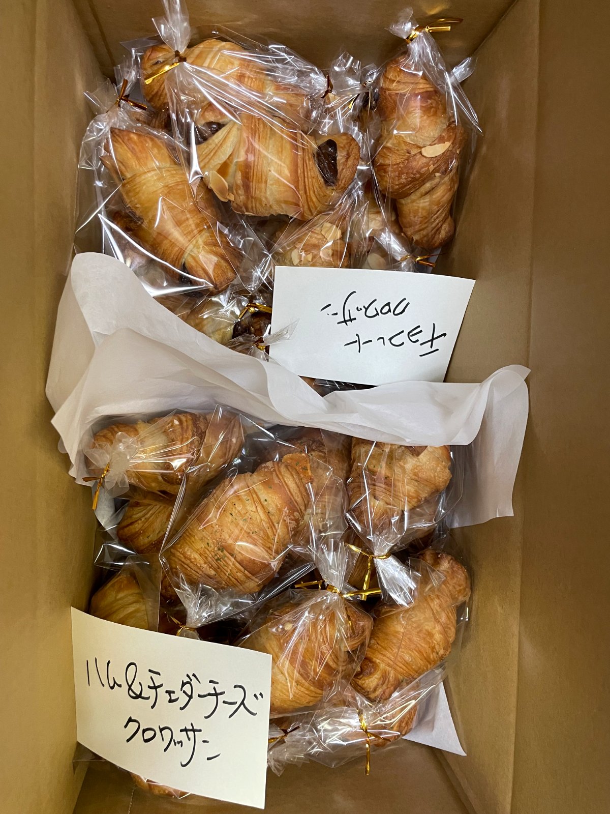 段ボールに詰めた個包装のクロワッサンと品名カード